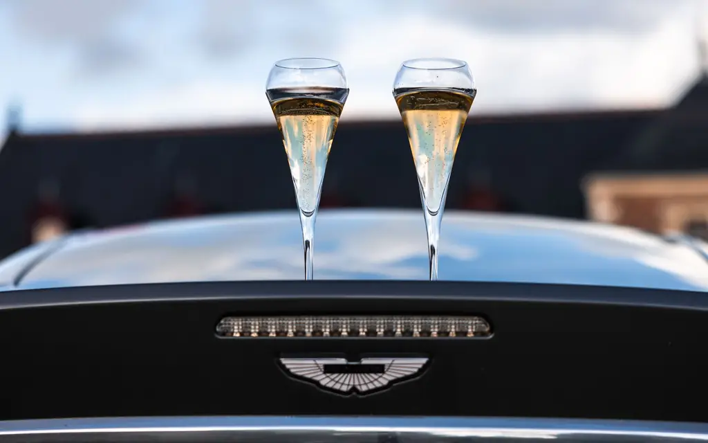 Two champagne glasses on the bonnet of a black car