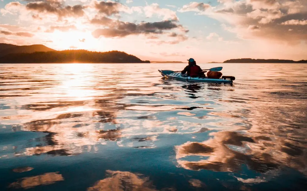 A kayaker on calm water at sunset
