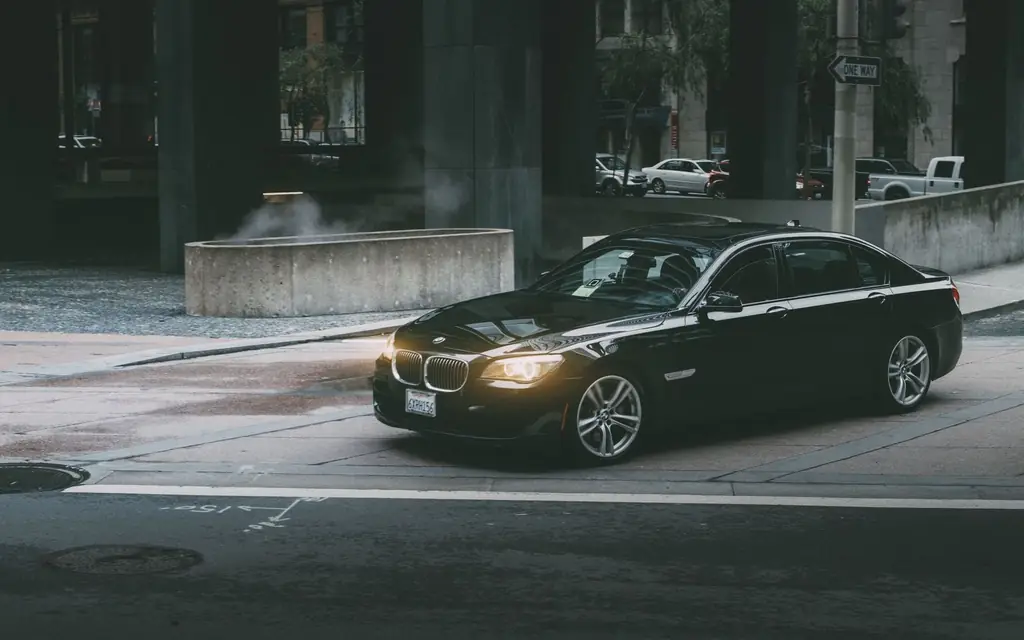 A black luxury car on a city street at twilight